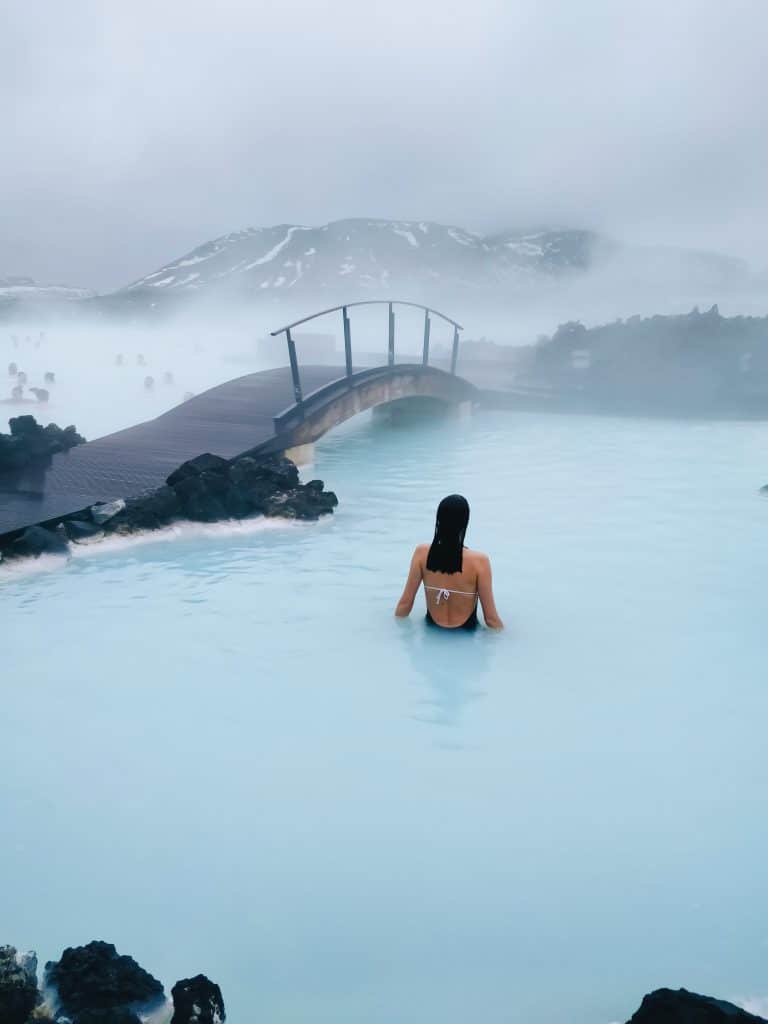 Een foto van de Blue Lagoon in IJsland, met stoom boven het warme water en een brug op de achtergrond