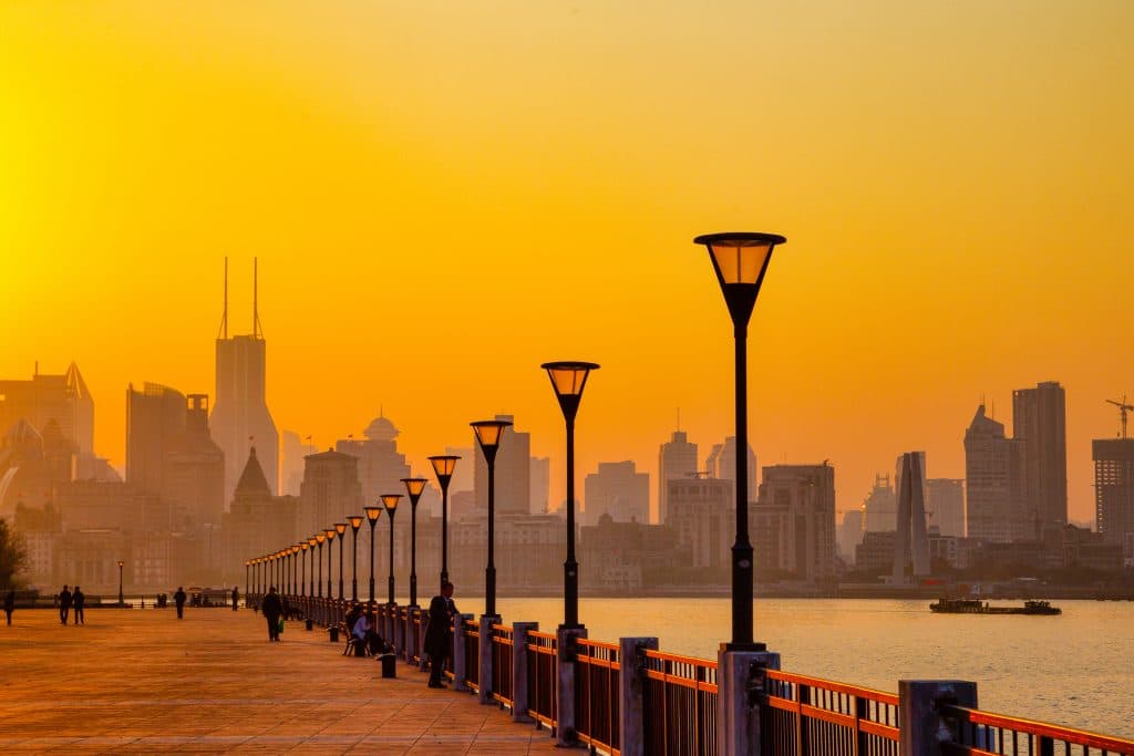 Wandelaars langs rivier bij zonsondergang in Shanghai