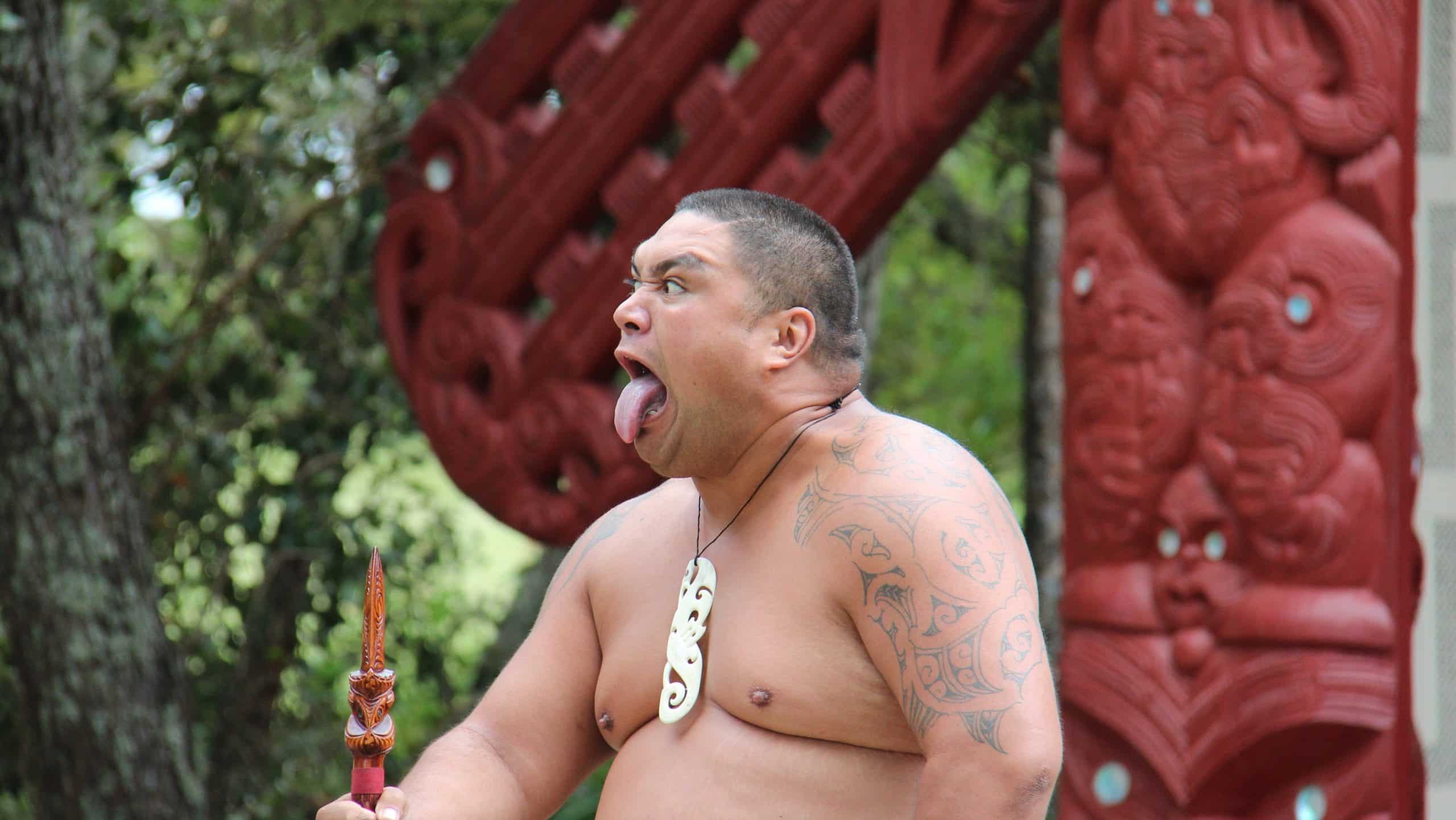Maori man met tatoeages voert ritueel uit
