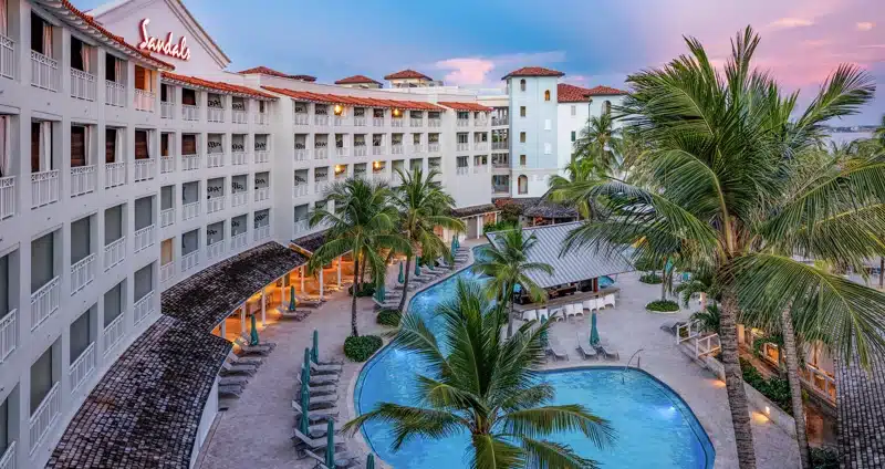 Zwembad en resortgebouw bij zonsondergang bij Sandals Barbados