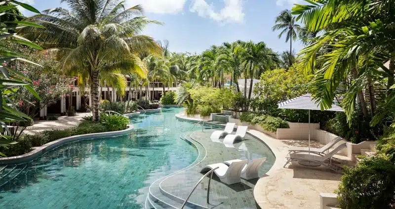 Zwembad met ligstoelen tussen palmbomen in Sandals Halcyon Beach