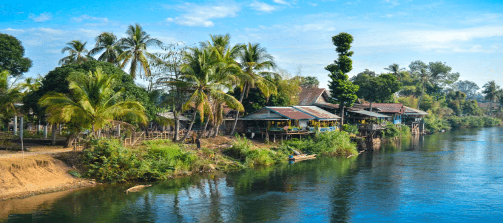 Rivieroever met huizen en palmbomen in Laos