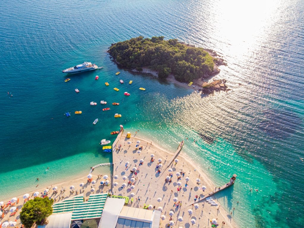 Strand met helder water en eiland bij Ksamil, Albanië