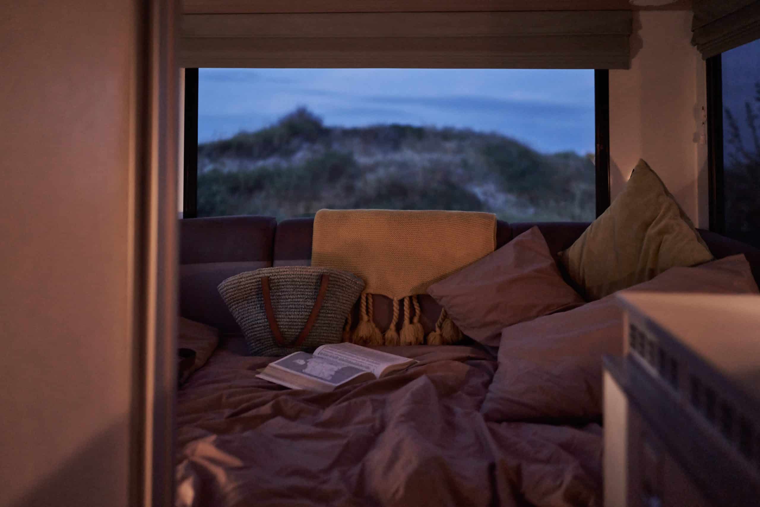 Bed in camper met boek en tas Nieuw-Zeeland