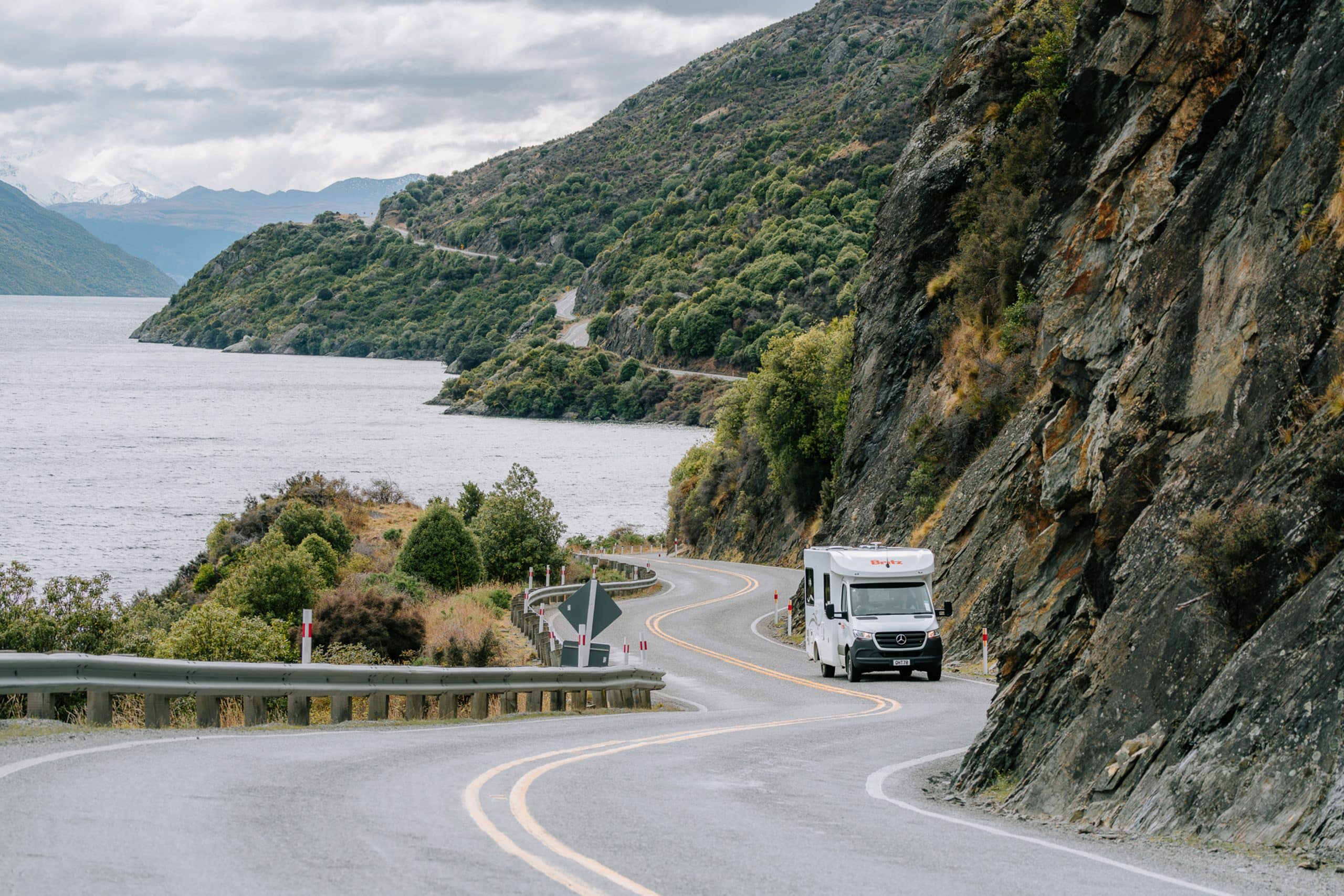 Camper rijdt langs bergmeer in Nieuw-Zeeland