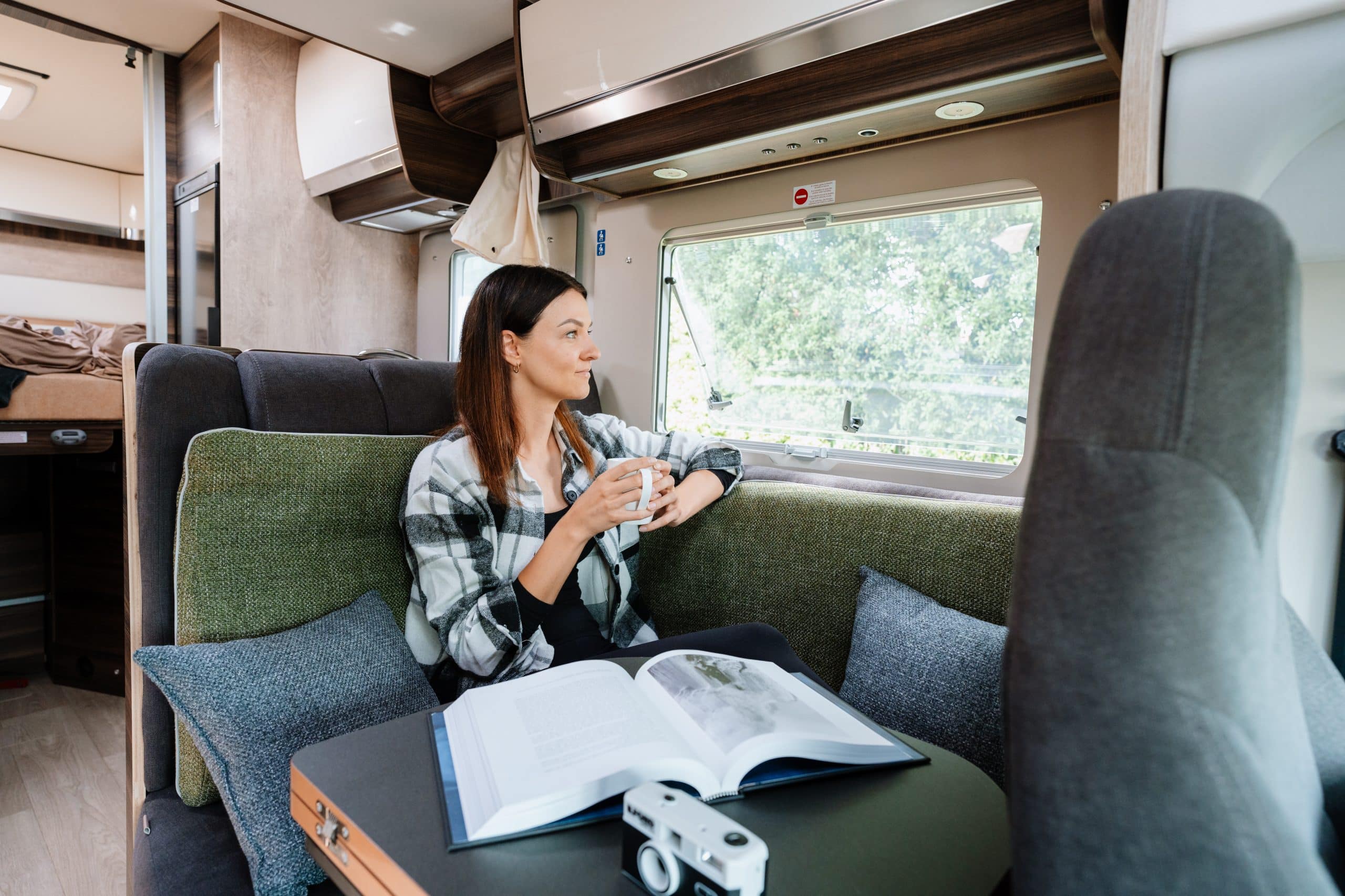 Vrouw leest met koffie in zithoek camper Nieuw-Zeeland