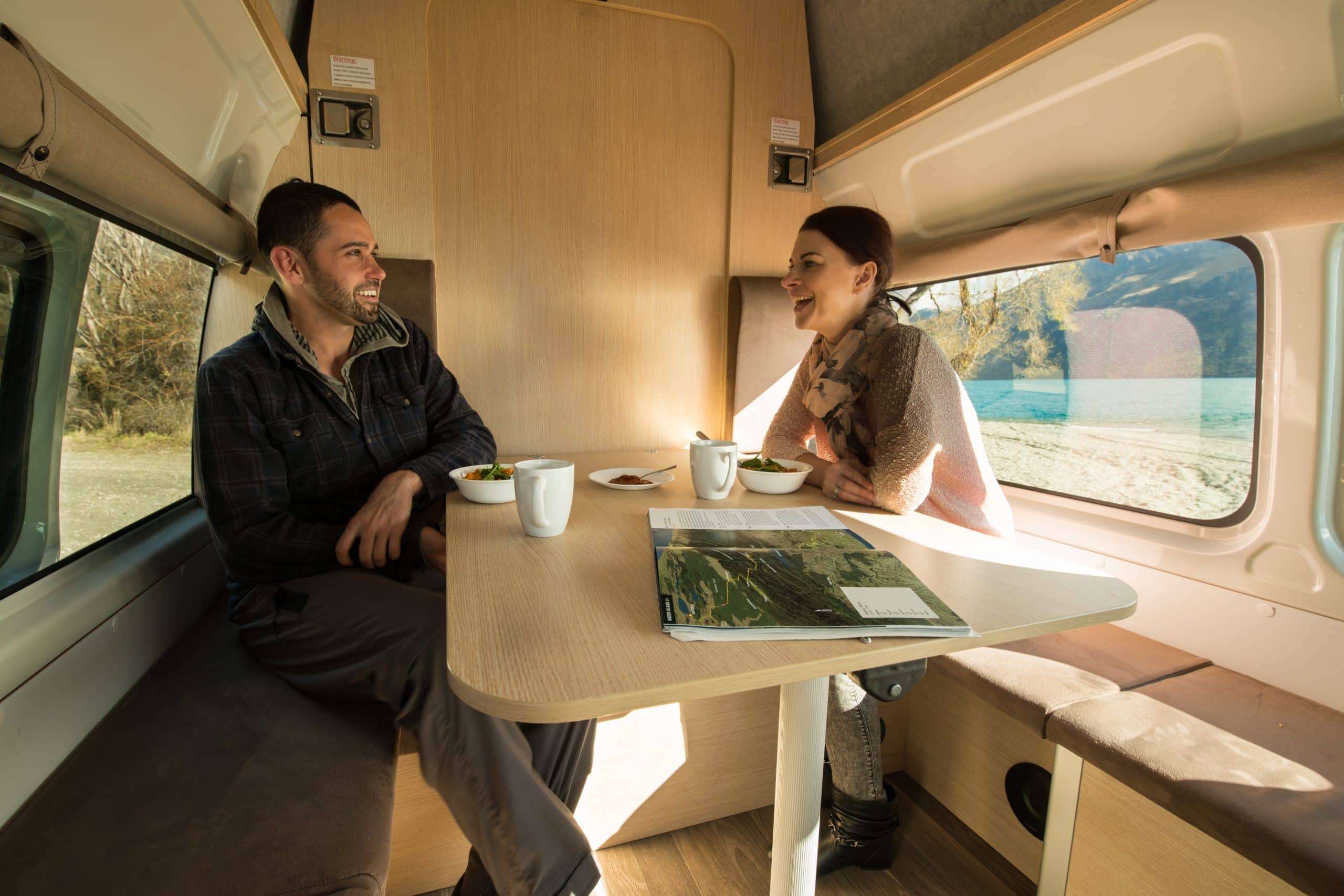 Twee mensen eten aan tafel in Hitop camper Cheapa Campa, Nieuw-Zeeland