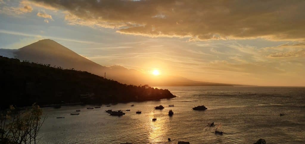 Zonsondergang met boten en vulkaan op Bali