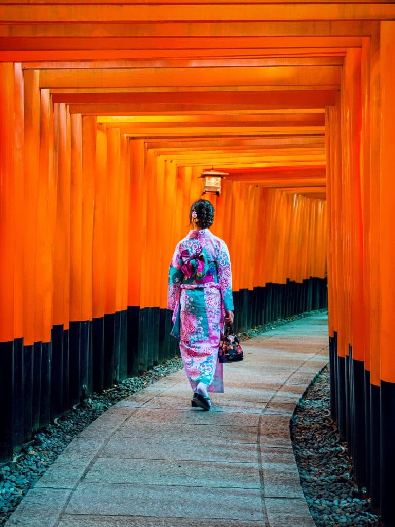 Vrouw in kimono in oranje torii-pad, Japan