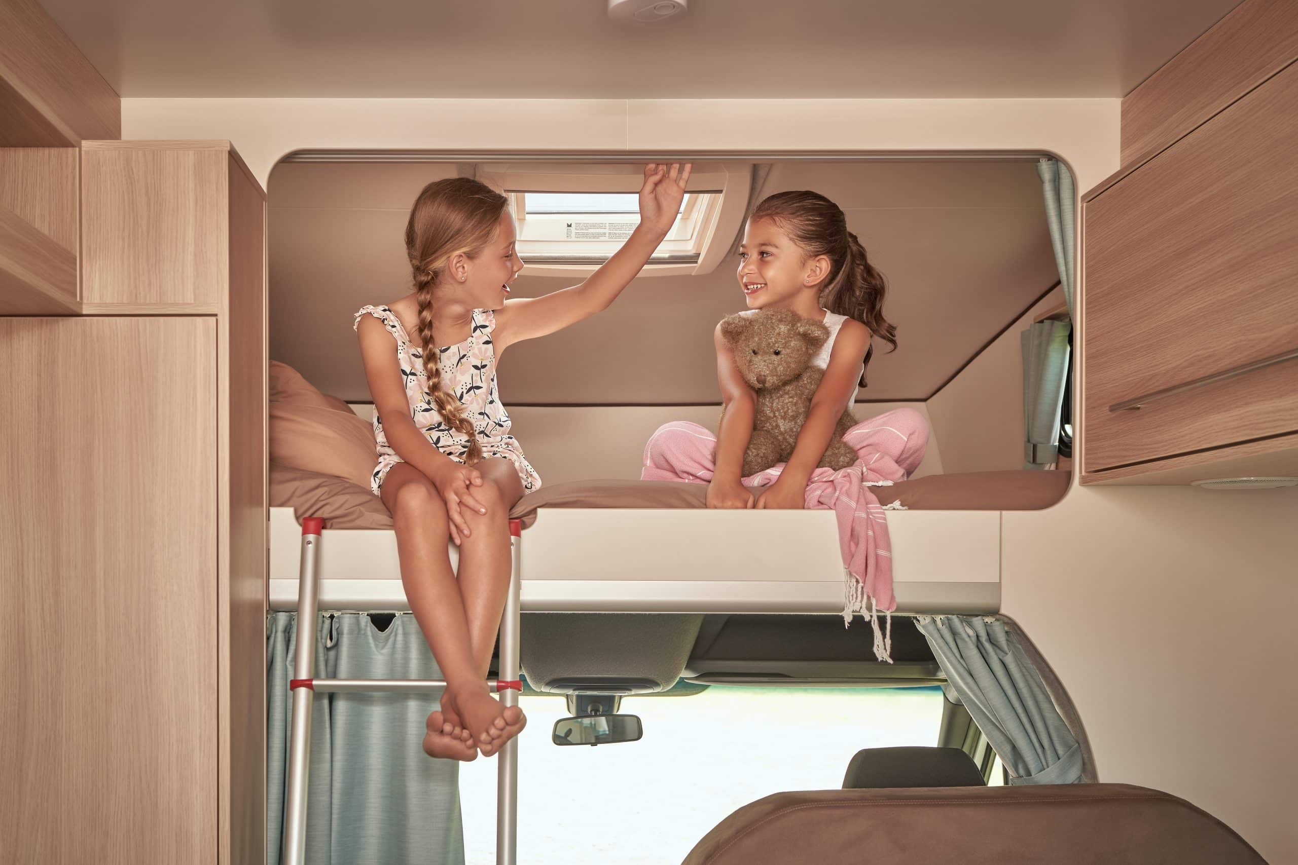Twee kinderen in alkoofbed in camper