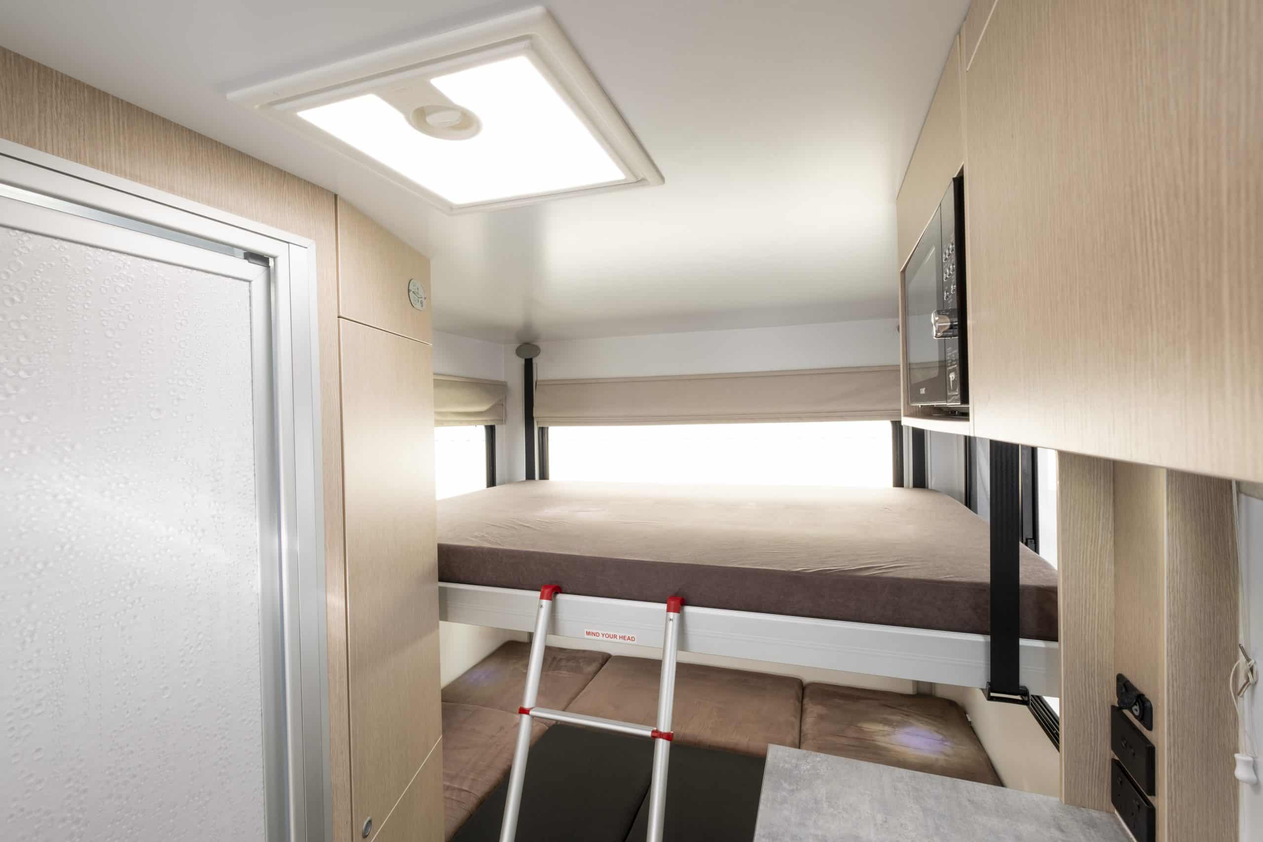 Camperinterieur met bed en trap in Nieuw-Zeeland