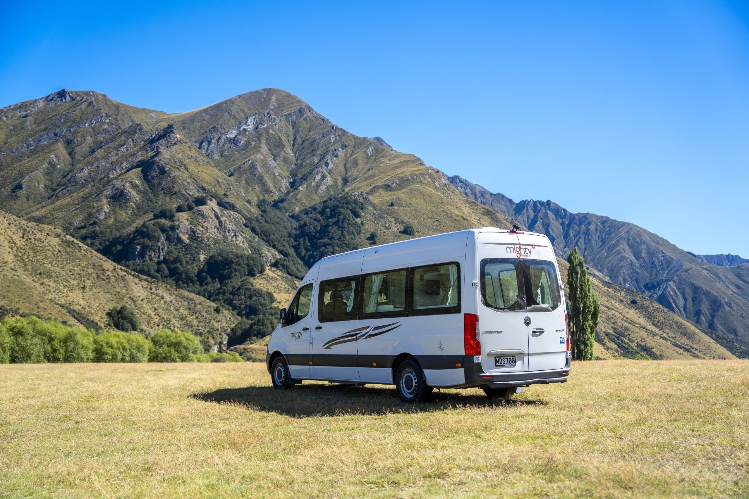 Achterkant Deuce camper in graslandschap Nieuw-Zeeland