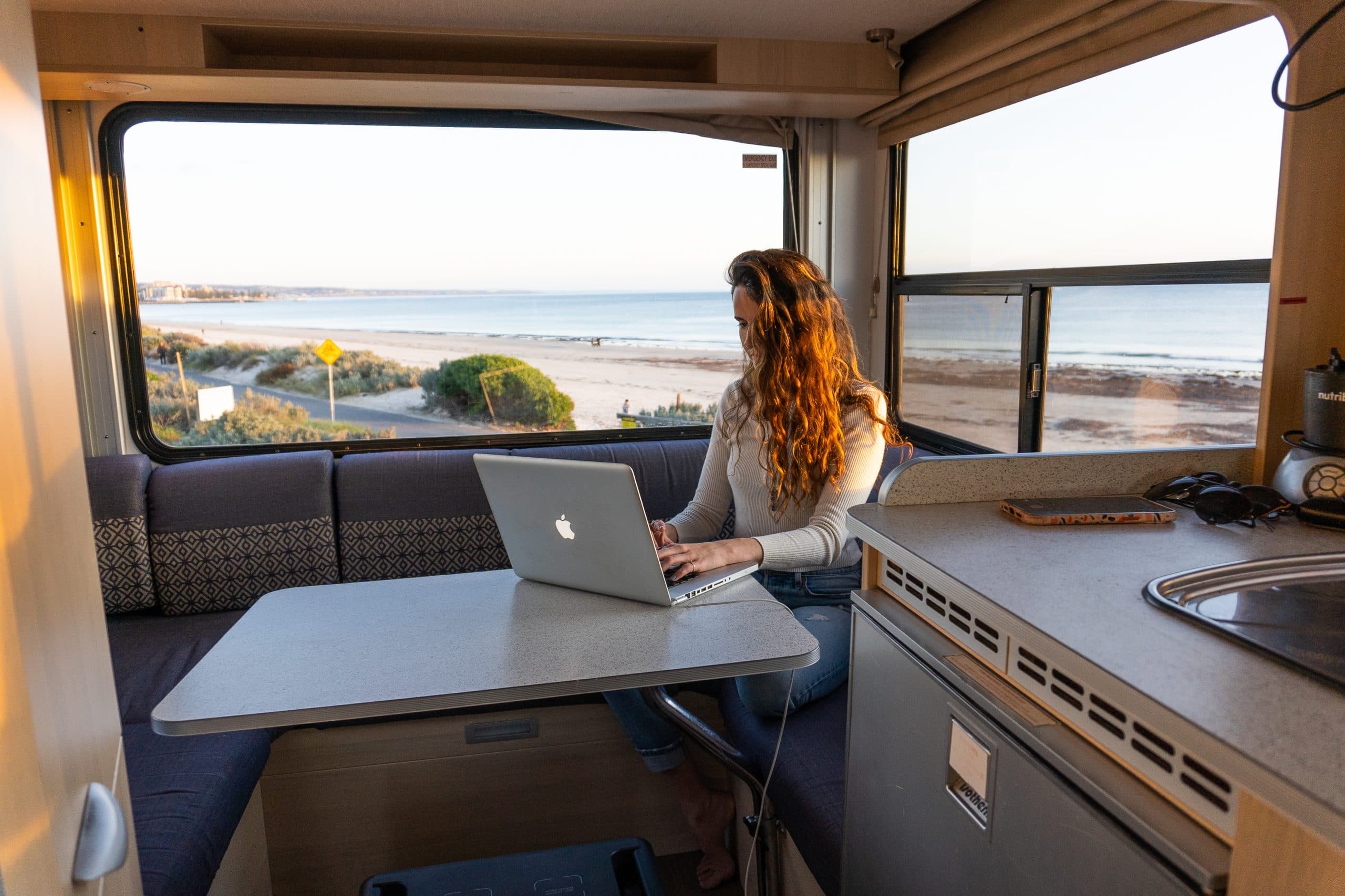 Vrouw werkt op laptop in camper Nieuw-Zeeland