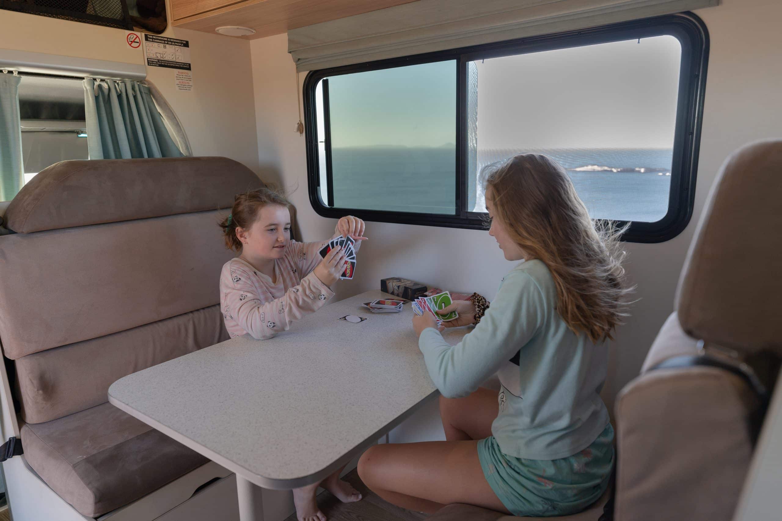 Kinderen spelen kaartspel in camper Nieuw Zeeland