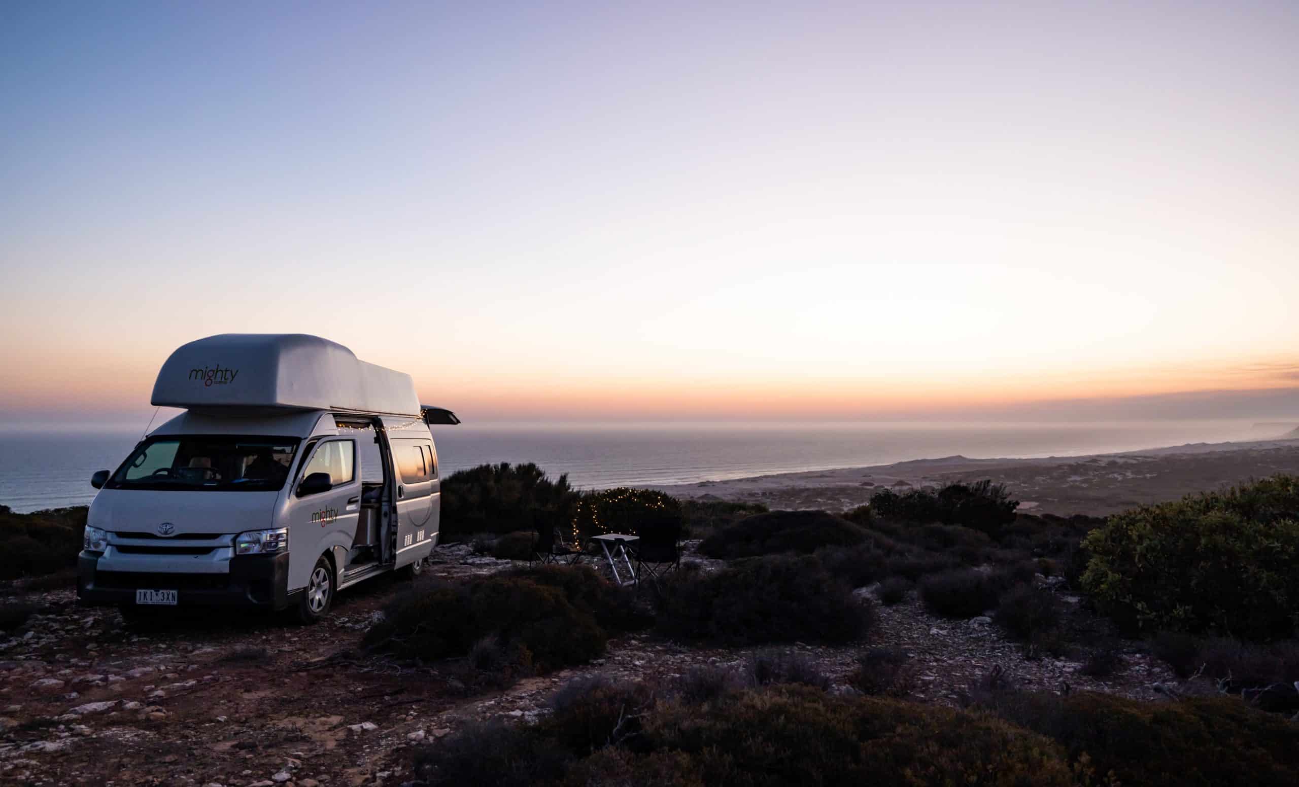 Camper op klif bij zonsondergang Nieuw-Zeeland