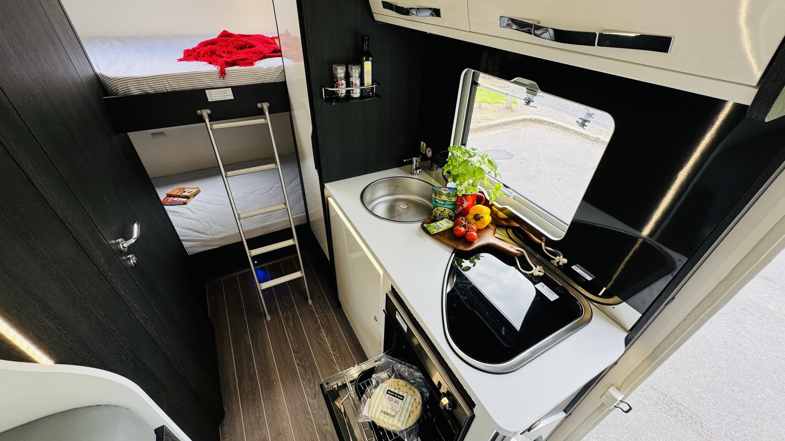 Eettafel en keuken in camper met zicht op bedden