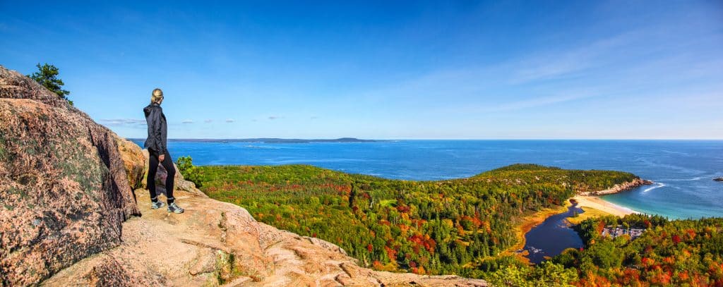 Wandelaar kijkt uit over kust en bos in Maine