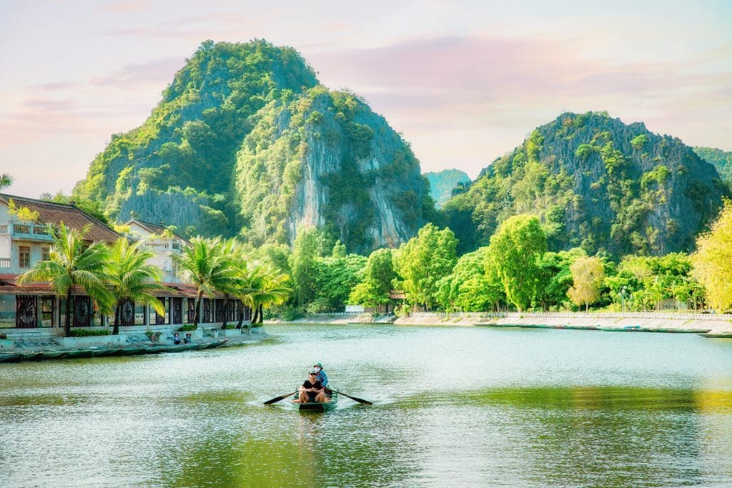 Rotsformaties en roeiboot op rivier in Vietnam