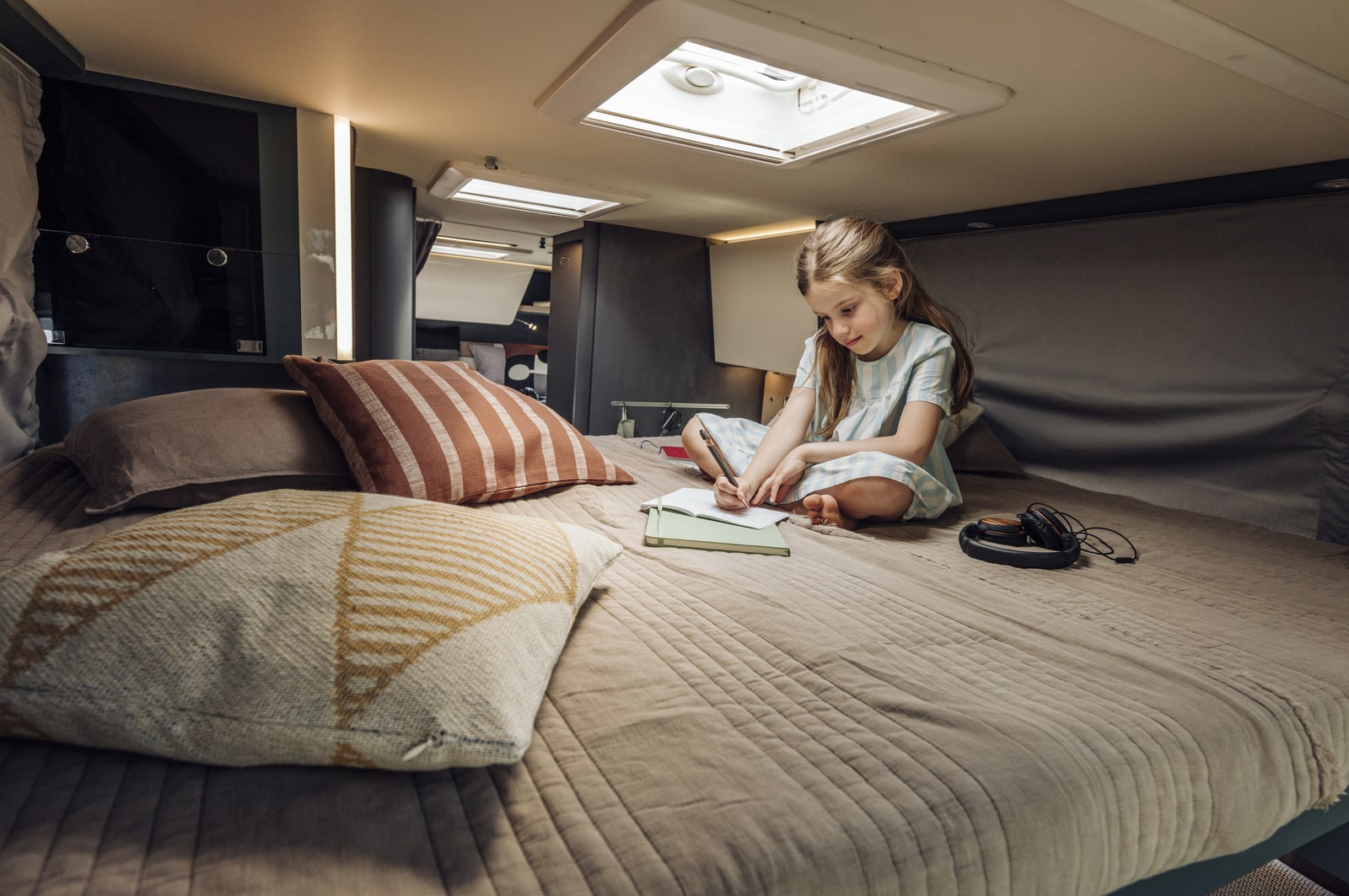 Meisje tekent op bed in camper Nieuw-Zeeland