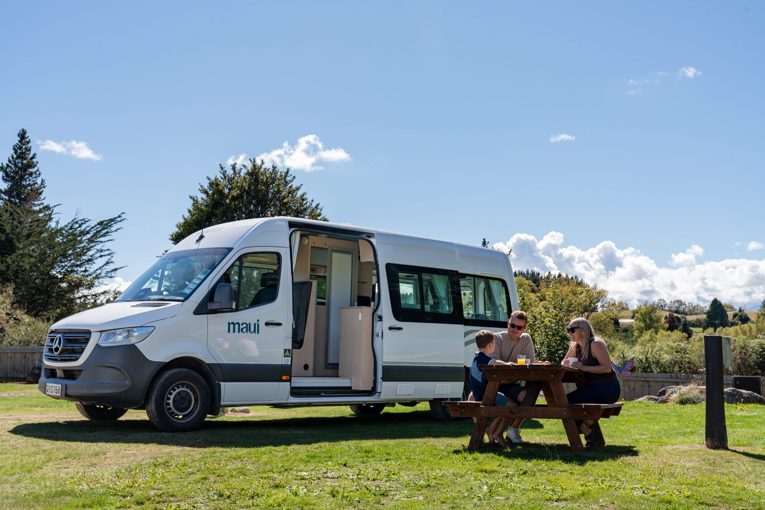 Camper met gezin aan tafel bij camper Nieuw-Zeeland