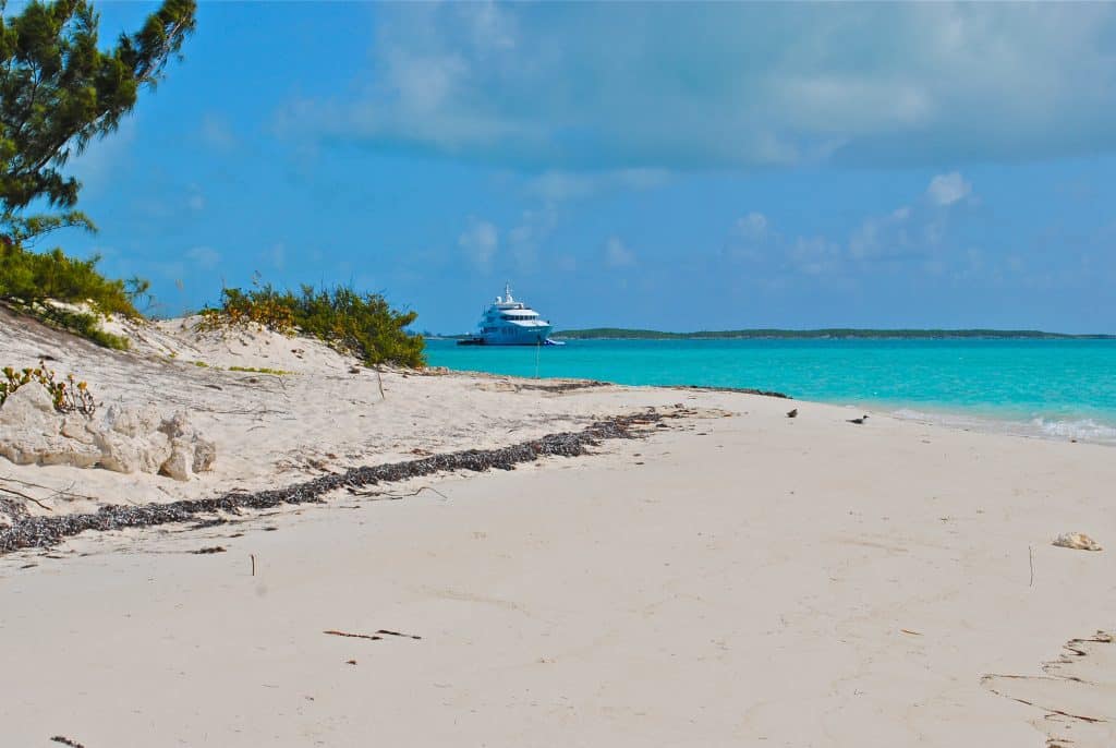 Witte zandstrand met jacht op turquoise water, Bahama's